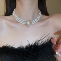 Détail macro d'un tour de cou à trois rangs de perles avec un fermoir doré orné de strass - Three Layer Pearl Oval Clasp Necklace / Or-Perle 5mm