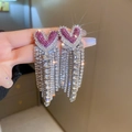 Dettaglio macro di orecchini a cuore rosa con nappe di strass tenuti in mano con cura - Perno in Acciaio - Orecchini a Pendente a Cuore Rosso Rosa