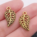 Leaf-shaped alloy pendant in antique bronze finish shown on fingertips for size scale - Antique Gold