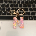 Macro view of a resin letter N keychain with colorful heart sequins on a keyboard - Letter N