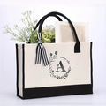 Detail of canvas tote bag featuring floral letter A print and striped ribbon accent - Letter-A