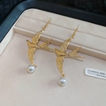 Detailed close-up of golden swallow earrings with white pearls on a beige velvet tray - Ear Hook - Gold