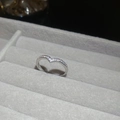 Vue macro d'une bague en V argentée sertie de zircons cubiques sur un support gris - Argent - Incrustation Pavé en V