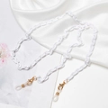 Detailed view of white acrylic link chain with gold lobster clasp on silk fabric - Pure White