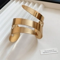 Dettaglio ravvicinato del bracciale a tripla spirale dorata con finitura a specchio lucida - Stile Spirale Incrociata a Più Strati / Oro