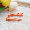 Close-up of orange gradient metal hair clips on a lace background with wooden tray - Orange