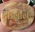 Pietra palmare in agata a strisce marroni con incisione dorata della parola Belief - Agata Pazza