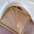 Macro shot of gold swan pendant with pink gemstone and crystals on silk fabric - Pink Diamond Swan Necklace (F225) / Gold/Pink