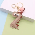 Dettaglio portachiavi a forma di dinosauro in pelle PU beige e marrone con gancio in metallo - Cachi