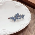 Detailed macro shot of blue rhinestone butterfly hair clip in a white decorative tray - Double Butterfly / Blue