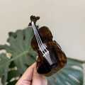 Handheld violin shaped acetate hair claw clip with tortoise shell pattern on leaf background - Violin