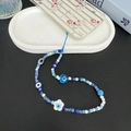 Dettaglio del cordino per cellulare bohémien con perline blu malocchio e elemento fiore - Malocchio Blu