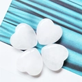 Polished white heart-shaped natural crystal stones displayed on a striped background - White Jade