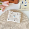 Detail of floral canvas wallet with blue heart button on a cozy straw mat background - Beige