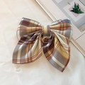 Brown and blue plaid fabric bow hair clip presented on a decorative book background - Yamabuki Plaid