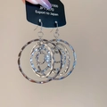 Nahaufnahme der silbernen, mehrlagigen Hammerschlag-Ohrringe an einem Display-Anhänger - Silber