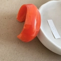 Macro detail van een brede acryl manchetarmband met oranje marmeren textuur op keramiek - Oranje