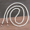 Detail of white round pearl crossbody chain with silver lobster clasps on wood background - 10mm Pearl Crossbody (Silver Clasp) / 118cm
