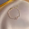 Dettaglio di un bracciale dorato a doppio strato con perle, cristalli e ciondolo a fiore - Doppio Strato Perla Fiore Chiusura / S217 Oro
