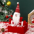 Pluche Kerstman met lange rode muts en sneeuwvlokpatroon zittend op een kerstcadeau - Kerstman