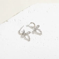 Detail view of silver bow-knot earrings with pavé zircons on white marble stone - Bow Knot Zircon Stud