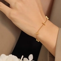 Minimalist gold-tone bamboo bar link bracelet shown on wrist over a brown blazer - 16+5cm / Gold