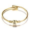 Macro detail van 18K gouden spiraal armband met hartvormige hanger en gravure van de letter G - Letter G