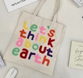 Detail of chenille letter embroidery on cream canvas tote bag with lifestyle accessories - Beige