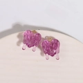 Dettaglio macro di due ciondoli a cuore in resina viola traslucida con effetto fuso - Viola