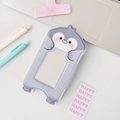 Cute gray penguin shaped card holder and polaroid photo album on a minimalist desk - Penguin