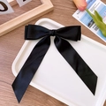 Detail of elegant black satin double bow hair clip on a white tray with tulip decor - Black