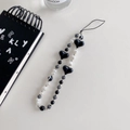 Detail shot of black heart beads and striped pearls phone charm on minimalist background - Heart Striped Beads