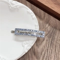 Close-up of a silver rectangular hollow hair clip with blue rhinestones on a white plate - Rectangle / Blue