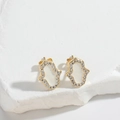 Macro shot of gold Hamsa hand stud earring with white inlay and sparkling zircons - Gold White Hamsa Hand