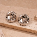 Makro-Detail von silbernen gedrehten Metallohrringen auf einer Naturstein-Plattform - Silber