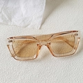 Close-up of translucent brown rectangular sunglasses with silver metal hinges on textured surface - Champagne