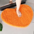 Absorbent orange heart-shaped chenille bath mat on gray tile floor for bathroom - Orange