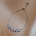 Detail of adjustable silver bracelet with six halo-set cubic zirconia stones on silk fabric - Round Halo Zirconia Drawstring Adjustable Style / Silver