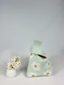 Detail of light green knitted bucket bag featuring white daisy patterns and handle texture - Green Daisy