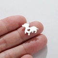 Detail of a small stainless steel puppy charm with heart cutout held by fingers - Steel