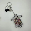 Macro detail of turtle keychain with colorful rhinestones and black fabric tassel - Multi-color