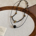 Detail of layered necklace featuring irregular tiger eye stones and black beads on wood - Black & Coffee (Two-piece Set)