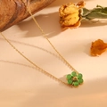 Detail van gouden bloemenketting met groene kattenoogstenen op een beige getextureerde achtergrond - Gouden Groene Kattenoog Ketting