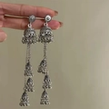 Detailed close-up of vintage silver Jhumka earrings with ornate bell tassels held by hand - 4# Steel Pin-Silver