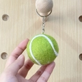 Handmade green wool felt tennis ball keychain with metallic ring on a wooden background - Tennis Ball