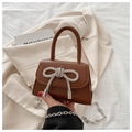 Macro detail of brown mini bag with sparkling rhinestone bow and silver chain strap - Tan