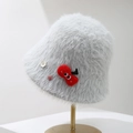 Close-up of a fuzzy light grey plush bucket hat with decorative buttons and a red patch. - Light Gray