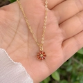 Collier en or pour femme avec pendentif fleur en zircon orange tenu dans la main - Rouge
