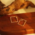 Close-up of minimalist golden square hollow stud earrings on a dark wooden surface - Square Hollow Studs(ZHE1427金)