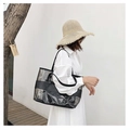 Borsa tote in PVC impermeabile con finiture in pelle nera indossata da una modella al mare - Nero